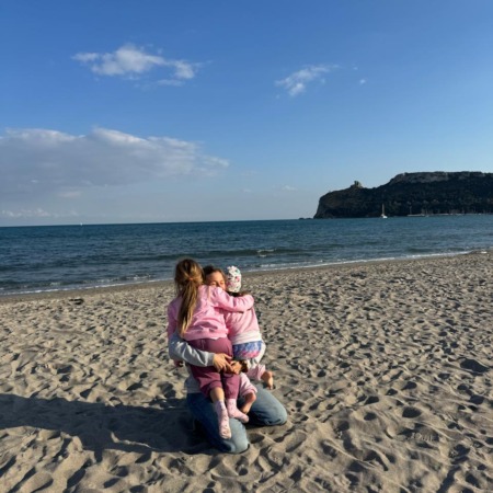 BBeatrice Mazza abbraccia le sue bambina su una spiaggia in sardegna